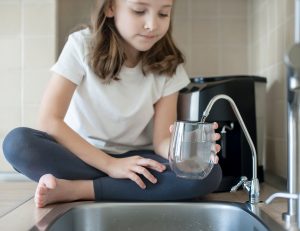 Little Girl filling a glass of water from the Tap 