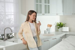 Woman drinking tap water from glass in kitchen