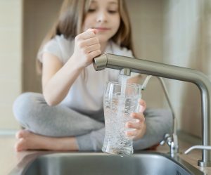 Little child fill drinking water in Glass in kitchen tap