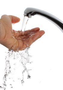 Hand being washed in running water isolated on white